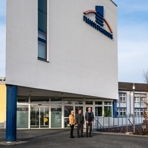 Klinikgeb&auml;ude mit drei Personen im Vordergrund