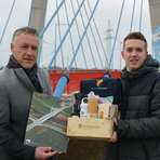 Landrat Carsten Michaelis überreicht dem Sieger des Fotowettbewerbs des Monats November eine Präsentkiste vor der Schrägseilbrücke in Schlunzig